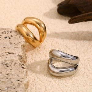 Polished 18K gold and silver lip-shaped stainless steel rings on a stone textured background