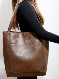 Détail du sac cabas vintage en cuir marron avec poche porté par un mannequin