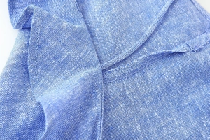 Macro detail of blue linen blend fabric featuring high-quality double needle stitching