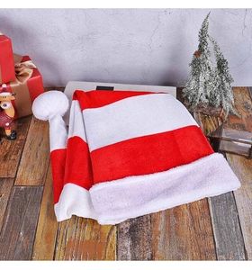 Close-up of a striped velvet Christmas elf hat with plush white pompom on wooden floor