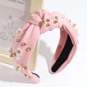 Detail of pink fabric headband with twisted knot, pearls, rhinestones and white flowers