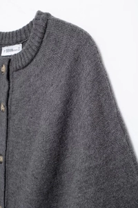 Close-up of dark grey knitted cardigan featuring a round neck and single-breasted buttons