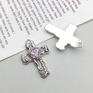 Detail view of silver cross pendant with pink enamel and heart shaped gemstone