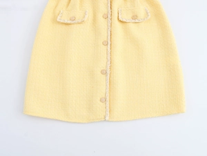 Detailed macro view of yellow tweed fabric with fringe pockets and elegant buttons