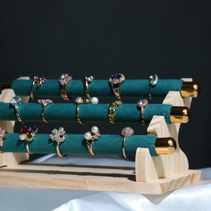 Three-tier emerald velvet and wood ring display stand with luxury jewelry on black backdrop