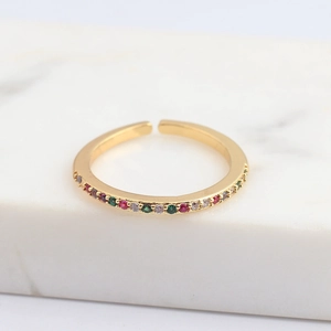 Close-up of gold open ring with micro-pave colorful zircon stones on marble stand