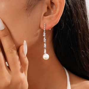 Close-up of elegant silver drop earring with sparkling zircon and a white pearl