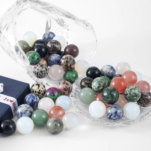 Polished natural crystal spheres spilling from a glass cup onto a white surface