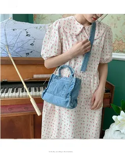 Detail of light blue denim mini bag with adjustable strap and front pocket detail
