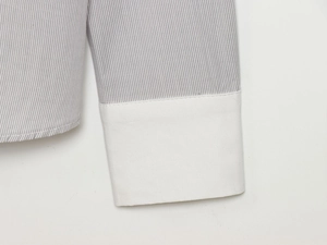 Detail shot of striped shirt cuff featuring neat stitching and white fabric splicing