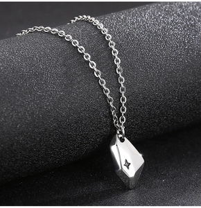 Macro detail of silver irregular geometric moon pendant with star engraving on dark background