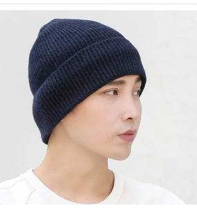 Close-up of side-view ribbed knit beanie in navy blue on a model with grey background