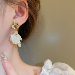 Close-up of elegant white petal drop earrings with shell texture and rhinestone detail