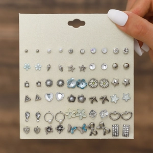 Detail shot of a 30-pair earring set featuring stars, bows, and faux pearls in silver