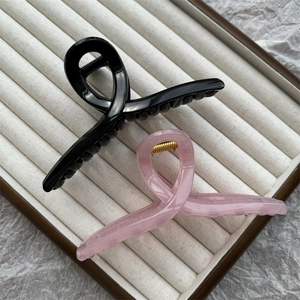 Detailed top view of black glossy and translucent pink claw clips on a beige jewelry tray