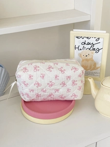 Quilted cotton makeup bag with pink bow patterns and white ribbon zipper pull
