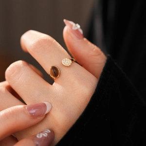 Détail d'une bague œil de tigre dorée avec oxydes de zirconium sur l'index d'un mannequin