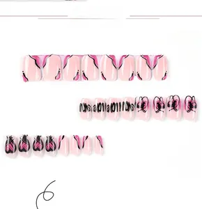 Detail view of pink press-on nails with black line art and heart graffiti patterns