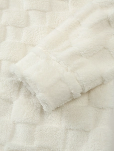 Détail du tissu polaire crème montrant le motif à carreaux gaufré et la texture du poignet