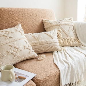 Bohemian beige tufted pillow covers with tassels on a cozy brown bouclé sofa
