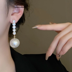 Macro detail of long drop earring with vertical rhinestones and a large white pearl