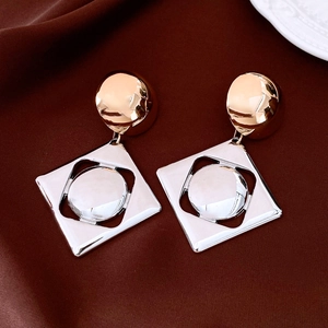 Detail of mixed-metal geometric earrings with gold studs and silver square pendants