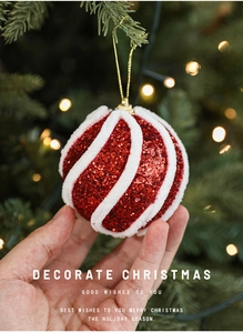Detail einer roten Glitzer- und weißen Samt-Weihnachtskugel gehalten von einer Person