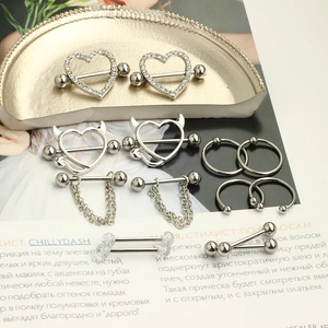 Set of 7 pairs of stainless steel nipple rings with heart and chain designs on a tray