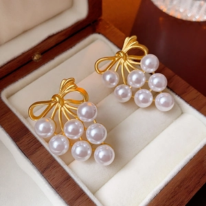 Detail of vintage pearl drop earrings with golden bow knots on white velvet lining