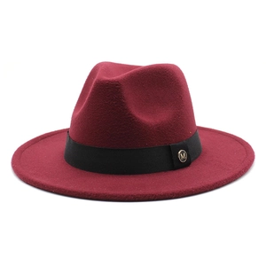 Detail of burgundy wool fedora hat featuring black ribbon and gold M letter metal pin