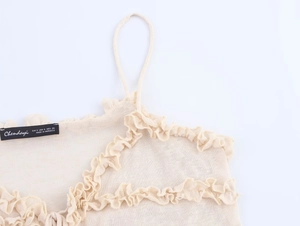 Detailed close-up of cream knitted camisole with ruffled neckline and thin shoulder straps
