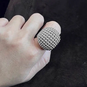 Detaillierte Nahaufnahme eines silbernen Kugelrings mit Perlenstruktur am Finger getragen