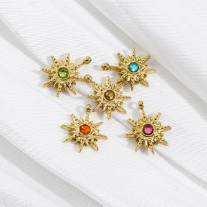 Five 14k gold star pendants with colorful zircon crystals on white silk background