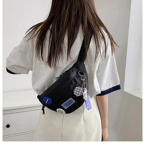 Close-up of black nylon crossbody bag featuring astronaut pendant and fashion tags