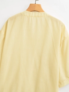 Detail view of yellow and white vertical striped blouse with knit texture on wood hanger