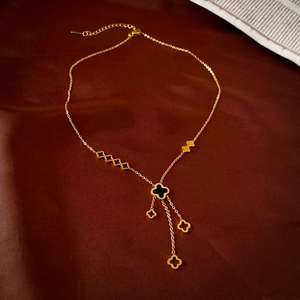 Détail du collier à pampilles trèfle doré avec incrustations noires sur soie sombre