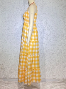 Detail of yellow checkered tiered dress featuring thin straps and cotton linen texture