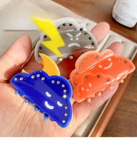 Detailed close-up of cloud-shaped hair claws with rhinestones and weather emoji designs