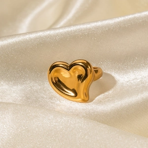 Detail shot of a polished 18K gold stainless steel heart ring on beige silk fabric