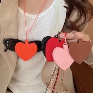 Detail of heart-shaped lychee leather pendants in various colors shown on a light sweater