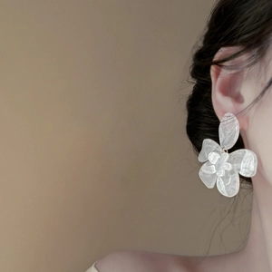 Elegant white resin flower earrings with marble texture on a female model side profile