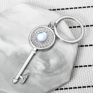 Silver key keychain with opal stone and rhinestones on marble hexagon coaster