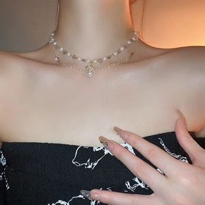 Double-layered pearl and crystal necklace with golden crown pendant on female model