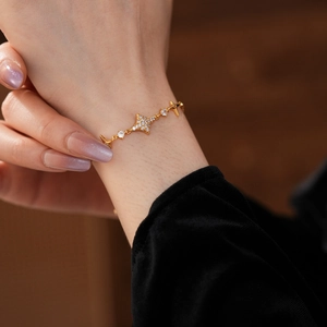Macro shot of gold star charm bracelet with shimmering zircons on black velvet