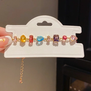 Detail of colorful gemstone bracelet with adjustable gold chain on display card