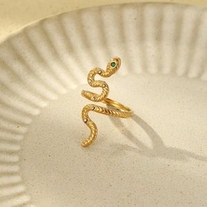 Detail of snake ring with green eyes and white gemstones on a ceramic plate