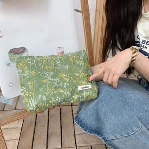 Detail of forest green makeup bag featuring delicate floral embroidery and brand label