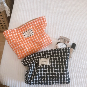 Macro detail of geometric cotton makeup bags in orange and black plaid with zip closure