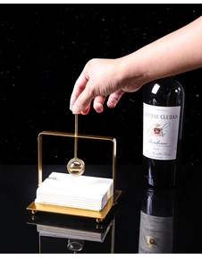 Detail of gold-plated stainless steel napkin holder with glass ball weighted pressure arm