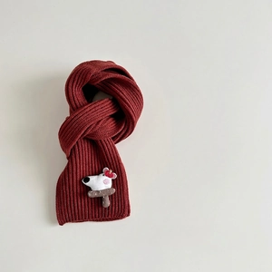 Detail of red cable knit scarf with 3D cartoon puppy patch and brown mushroom design